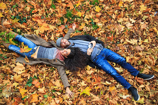 istock Young couple having fun and  lying down on leaves 585498486