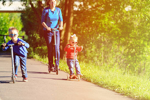 istock mother with kids riding scooters in summer 585500102