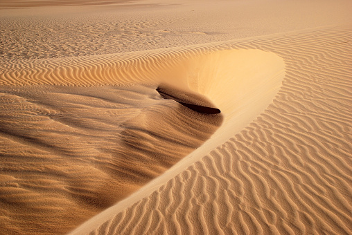 Wind formed beautiful temporary sand pattern in the desert. The sand looks like frozen waves.