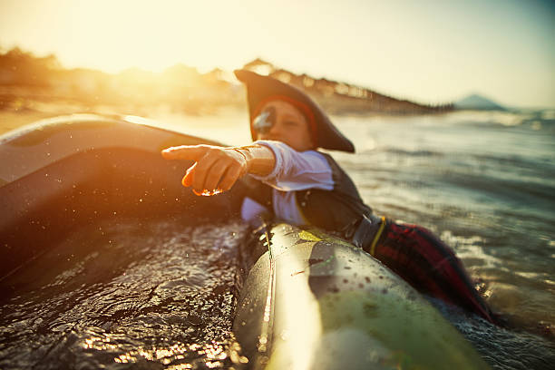 Little boy playing pirate on a sinking boat Little boy aged 6 pretending to be a pirate whose ship is just sinking. castaway stock pictures, royalty-free photos & images