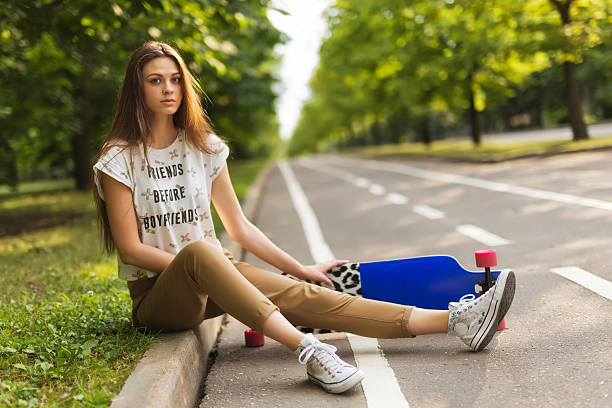 Beautiful young girl sitting in the park on the lorgbord stock photo