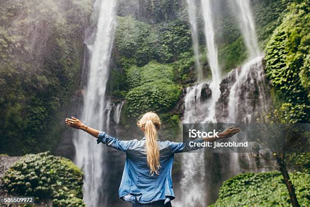 Mujer De Pie Junto A La Cascada Con Las Manos En Alto Foto de stock y más banco de imágenes de Catarata