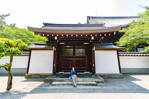 Young Japanese woman sitting and relaxing in the grounds of a Buddhist temple in Kyoto, Japan