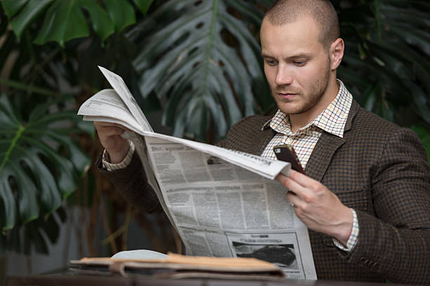 Businessman reading newspaper Businessman reading newspaper on chair at office building hall or cafe newspaper airport reading business person stock pictures, royalty-free photos & images