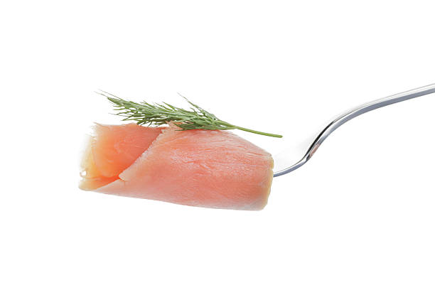 istock Salmon piece with dill on a fork isolated on white 585511438