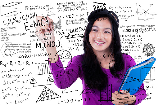 Beautiful schoolgirl writes formula of math and science on the whiteboard, isolated on white background