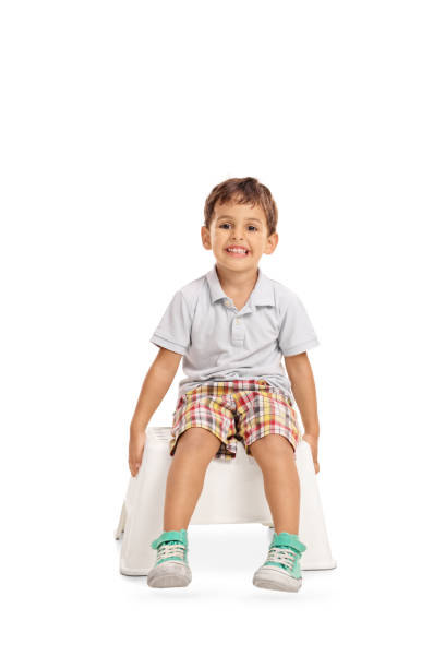 Vertical shot of smiling kid sitting on a chair and looking at the camera isolated on white background