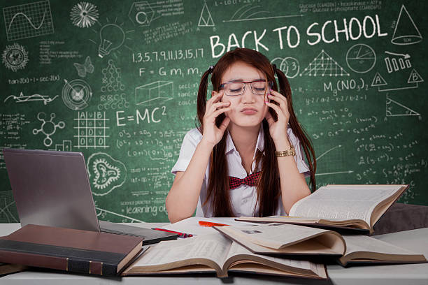 istock Confused schoolgirl with books in class 585514602
