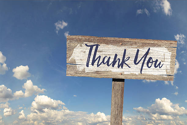 Thank you wooden rustic sign against a blue sky with clouds