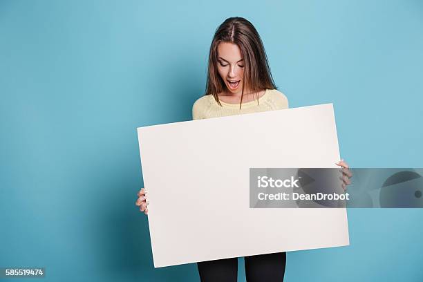 Beautiful Young Girl Holding Empty Blank Board Over Blue Background Stock Photo - Download Image Now