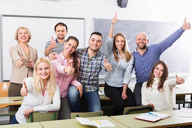 Portrait of smiling teacher and adult happy students in classroom