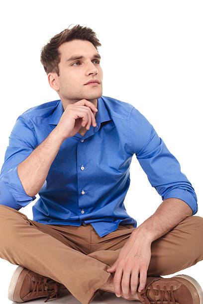 istock Pensive young man sitting with his legs crossed 585520814