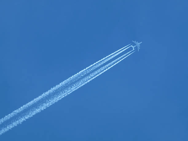 istock Passenger jet flying in clear blue sky, leaving white trail 585523484
