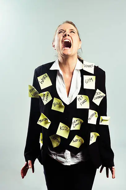 A furious businesswoman covered with adhesive note reminders of things to do has become a human noticeboard. She's yelling in frustration.