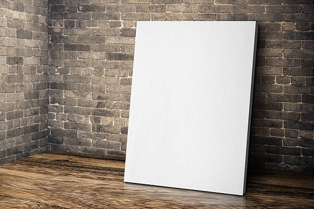 istock Blank canvas frame leaning at brick wall and wood floor 585524256