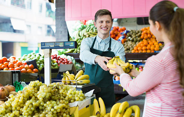 istock Young female customer buying yellow bananas 585524324