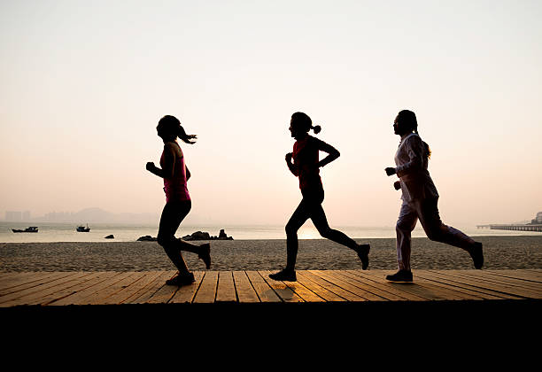 Three young women jogging along the beach.