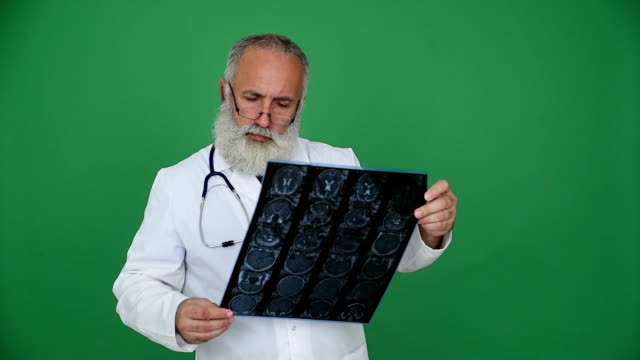 adult senior doctor looks picture MRI of the head on a green background