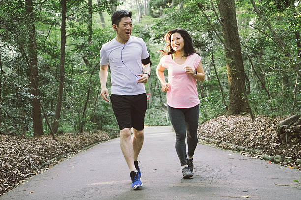 fröhliches japanisches paar läuft im freien in einem park - sports clothing jogging running 40s stock-fotos und bilder