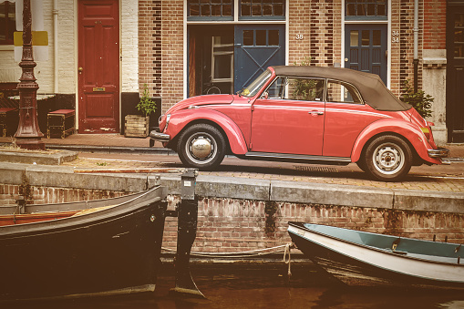 Amsterdam, The Netherlands - August 2, 2016: Retro styled image of a classic Volkswagen Beetle convertible parked alongside a canal in Amsterdam, The Netherlands