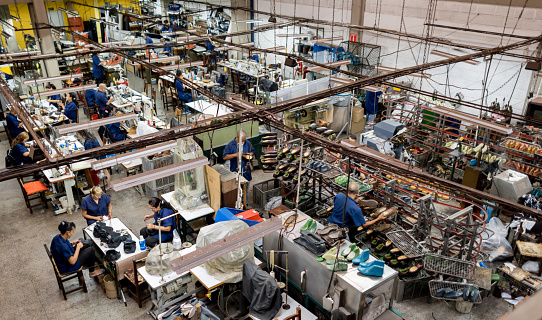 Group of Latin American people working in a factory making shoes - production line concepts