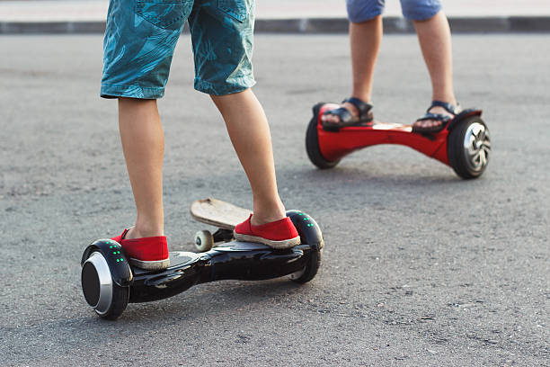 Boys stands on the black gyro scooter outdoors Young boys stands on the black gyro scooter outdoors, soft focus background hoverboard stock pictures, royalty-free photos & images