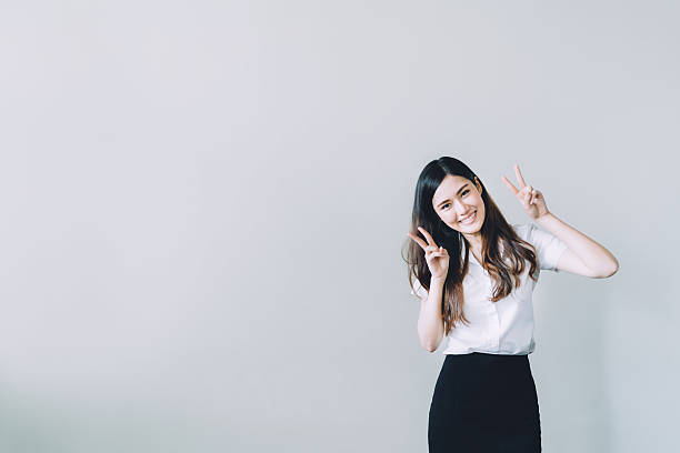 Asian university girl doing funny rabbit pose, with copy space