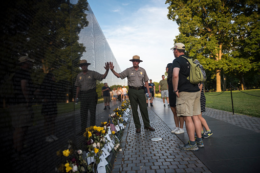 Washington D.C., USA - June 20, 2016: At the Vietnam Veterans Memorial in Washington D.C., a National Park Service ranger talks about the wall to visitors. Inscribed in the wall are the names of the more than 58,000 American military personnel killed during the war in Vietnam.