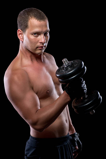 istock serious man with a heavy dumbbell on a black background 585595528