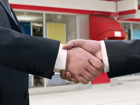 businessmen handshaking in front of a building
