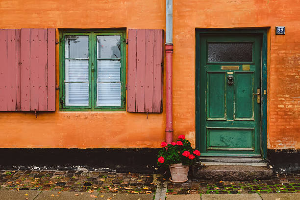 orange wand, grüne fenster und rote blumentopf - denmark copenhagen brick street stock-fotos und bilder
