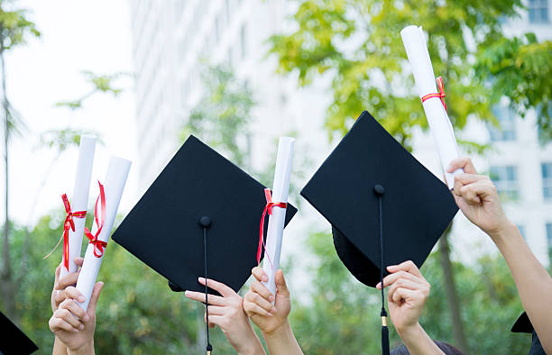 istock Graduates holding motarboards and diplomas 585598114