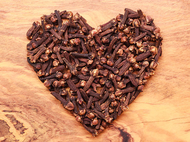 Heart form made from spice cloves on wooden background