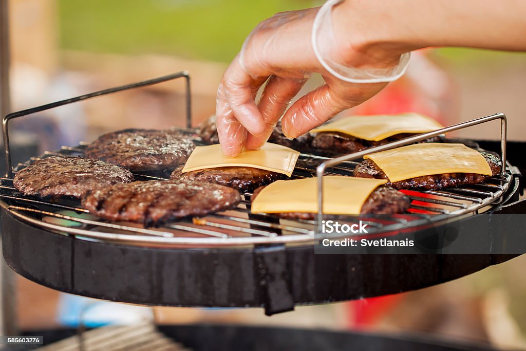 Man's hand, spread the cheese on the burgers Closeup of a man's hand, spread the cheese on the burger patties on the barbecue-party American Culture Stock Photo