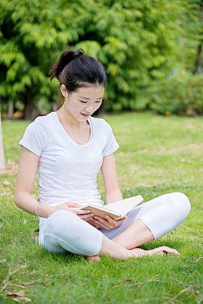 istock Young woman reading a book in park 585604088