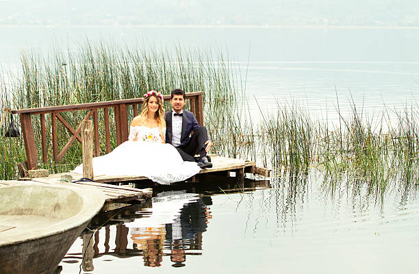 istock Bride and groom posing at a dock on the lake 585605006