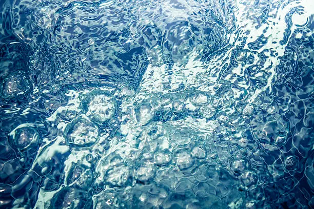 Photo of toned clear water whirlpool with bubbles and ripples