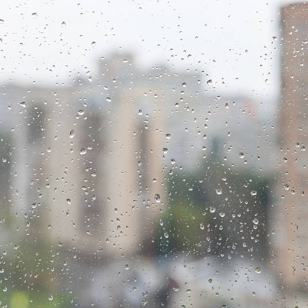 istock rain drops on window glass and blurred urban house 585607804