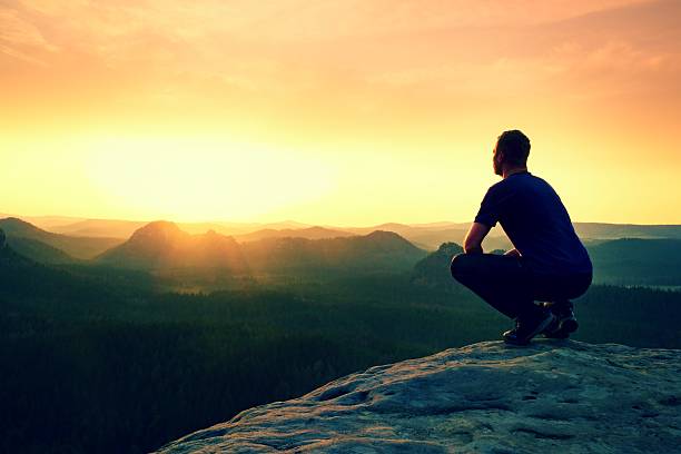 istock Tourist in squatting position on sandstone rock  watching into  valley 585608034