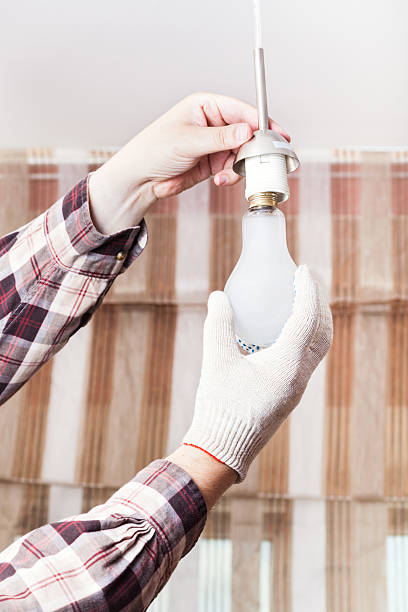 istock Electrician replace incandescent lamp in holder 585608210