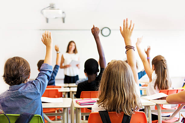 School kids in classroom School kids in classroom hand raised stock pictures, royalty-free photos & images