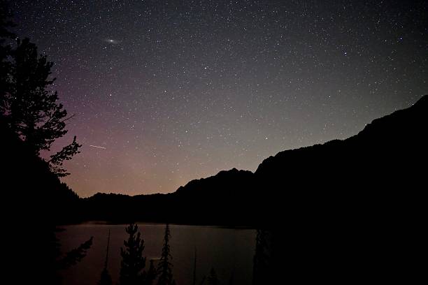istock Nebula and constellations in night sky over lake. 585610626