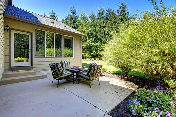 istock Cozy backyard concrete floor patio area with table set. 585613458