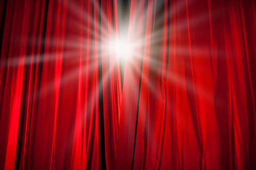 Red Curtain Opening with Stage Light Shining Through
