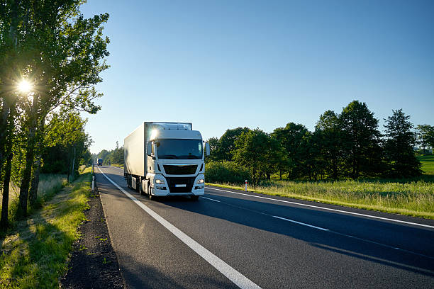 White truck arriving on the asphalt road.