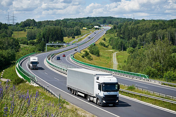 istock Trucks driving on a highway through a forested hill. 585614798