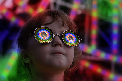 The little girl with glasses rides reflected in night illumination