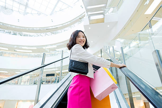 istock Attractive female shopper standing on escalator 585617740
