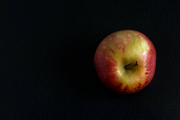 apple art top view with black leather background and space for design.