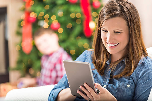 une femme de race blanche utilise une tablette numérique pendant la période des fêtes - family cheerful family with one child texas photos et images de collection